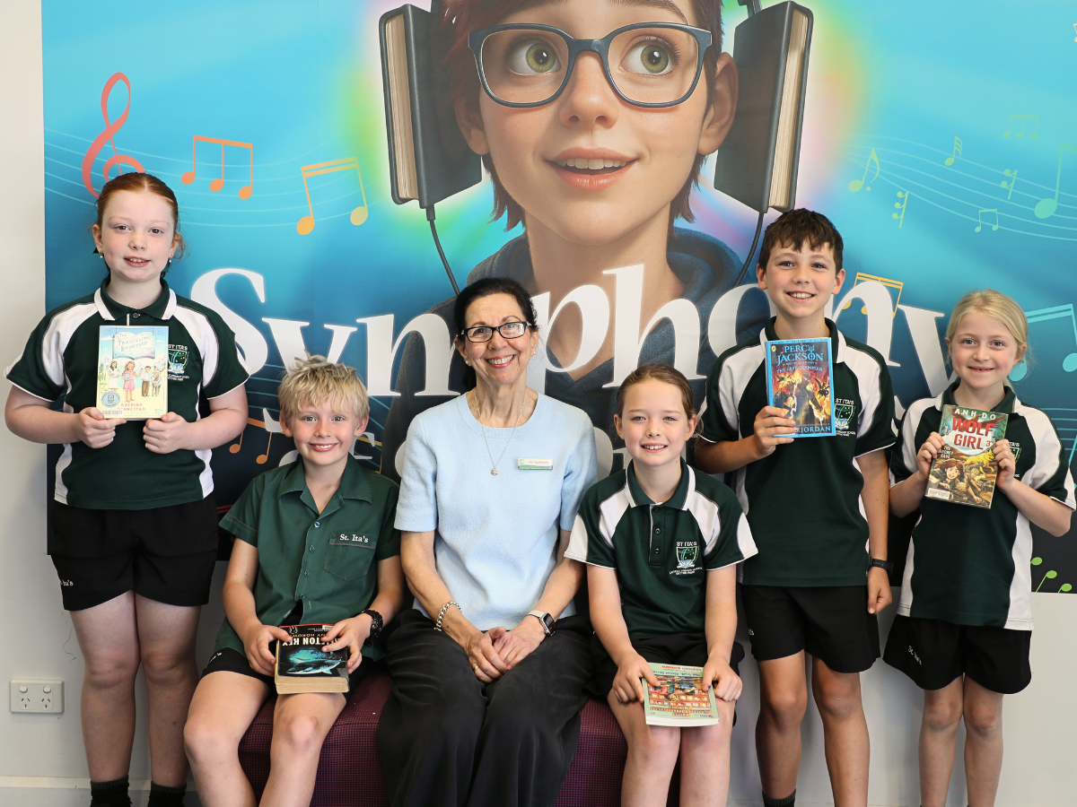 Teacher-Librarian Filia Papamanolis with students smiling to camera holding their current reading books.
